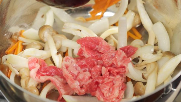 Add the vegetable oil again and reheat the pot. Add the onion, carrot and shimeji mushrooms. Lightly cook the ingredients. When the oil is distributed evenly, add in the beef slices. Continue to saute the ingredients.