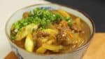 Verter la salsa de curry caliente sobre los fideos udon junto con los ingredientes. Finalmente, cubrir con la hoja de cebolla de primavera cortada.