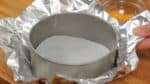Place a piece of parchment paper cut to fit into the bottom of the pan. Then, cover the outside of the pan with a large piece of aluminum foil.