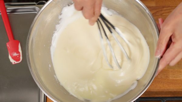 Like shown, lift the whisk from the bottom to gently combine the batter. Be sure not to break the foam. Mix until all of the white lumps of meringue have disappeared.