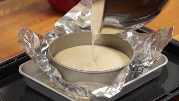 Pour the batter into a pan and place it into a deep tray. The pan has a removable bottom so be sure to cover it with relatively thick aluminum foil to avoid wetting the cheesecake. If your aluminum foil is too thin, you should cover the cake pan with 2 or 3 layers, making absolutely sure to avoid any leakage.