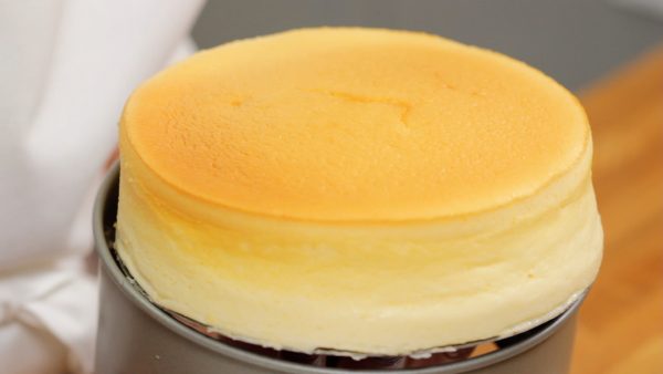 Remove the soufflé cheesecake from the pan. Gently lift the bottom. Be careful not to damage the side of the cake. Run an icing spatula along the bottom. Remove the bottom of the pan and place the cheesecake onto a cutting board.
