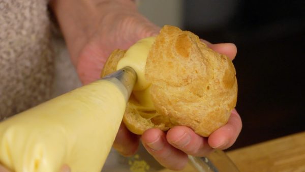 Put the pastry cream into a bag. Give it a little squeeze to remove the air inside. Open the pastry and squeeze a generous amount of the cream into it. You can also simplify the filling process by spooning the cream into the pastries.