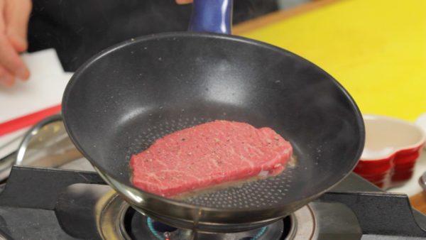 把鍋燒熱，倒入一茶匙剛才炒蒜剩下的油。把牛排放入鍋裡。先只煎一面，這樣上菜時牛排就是一種漂亮的褐色了。