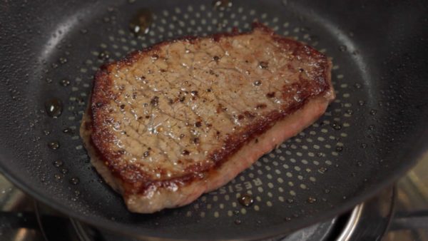Faites dorer le steak sur feu fort pour environ 1 minute et retournez-le. Faites cuire le dessous (côté quadrillage) sur feu fort pour 10 secondes. Ensuite, baissez le feu à feu doux et faites cuire 10 secondes de plus. Retirez et placez-le sur une grille. 