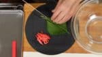 大葉は縦半分に切り、軸を取り除きます。大葉を重ねて千切りにします。こちらは生姜を梅酢に漬けた紅生姜です。みじん切りにします。