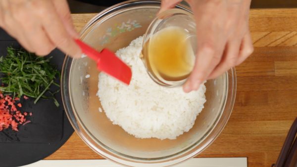 Place the fresh steamed rice into a bowl. Pour the sushi vinegar over the rice. With a rice paddle, toss to coat using a slashing motion to avoid crushing the grains.