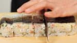 Flip the bento box and remove the pressed sushi. Wet the blade of a knife thoroughly. Make a cut in the plastic wrap and then slice off the oshizushi. You should clean the blade each time you cut off a slice. If the blade is coated with rice, it will be difficult to make clean cuts.