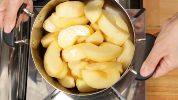 When the melted sugar begins to make a simmering sound, uncover and shake the pot up and down to bring the bottom of the apple to the top. This method will help to avoid breaking the shape of the apple. Occasionally mix the apple from the bottom with a wooden paddle.