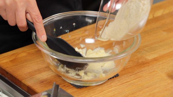 The unsalted butter should be at room temperature also and softened in a bowl. Add the sifted powder to the butter. Combine the mixture with a spatula.