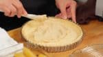 Saatnya mengisi kulit pie. Tambahkan krim almond ke dasar kulit pie. Ratakan dengan spatula.