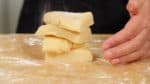 在刮板上撒上麵粉，把麵團分成4塊。把四塊疊起來，每層中間撒上點麵粉，用手把麵團壓平。