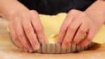 Farinez vos doigts et pressez la pâte sur les bords du moule. Veillez à presser la pâte dans les bords pour retirer les trous. 