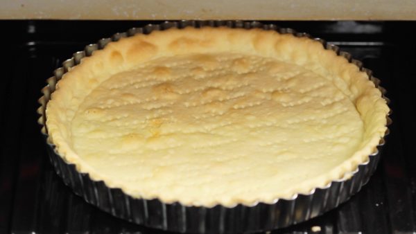 Preheat the oven to 190 °C (374 °F) and place the tart pan into it. Bake the tart at 190 °C (374 °F) for a total of about 20 minutes. To help brown the tart evenly, put on kitchen gloves and rotate the pan after about 15 minutes. Then, bake for 4 to 5 more minutes.