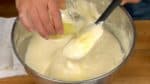 Wenn das Mehl vollständig unter gehoben ist, schüttet die vorgewärmte Butter gleichmäßig über den Teig. Hebt diese unter, indem ihr den Teig sanft anhebt und vom Spatel fallen lasst. Wiederholt diesen Vorgang etwa 50 Mal. 