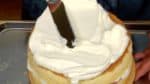 Drop a generous amount of whipped cream on top. Spread evenly with the frosting spatula while rotating the turntable.