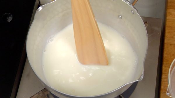 Cho sữa và đường vào trong nồi. Bật bếp và khuấy bằng thìa cho đến khi đường tan hết.