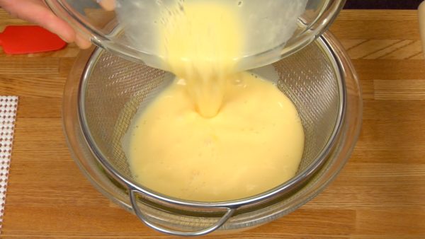 Cuela la mezcla de huevo con un colador de malla fina. Raspa el fondo del colador con una espátula. Remueve la espuma que haya con una cuchara. Vierte la mezcla con huevos en un contenedor o jarra desde donde sea fácil verter.