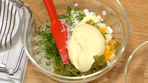 Pinch the parsley, chop into fine pieces and add it to the egg. Slice the pickled cucumber, stack them on top of each other and chop into fine pieces. Add it to the egg mixture. Add the mayonnaise and salt to the mixture.