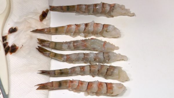 Cut the tips off the tails with a kitchen shears and remove the moist inside. Make cuts diagonally along the prawn stomachs. Press the prawns on their back and break the stringy parts. This process will prevent the prawns from curling up when heated. Finally, lightly sprinkle on salt.