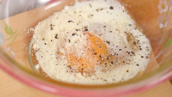 Do větší mísy rozklepneme vajíčko a dobře ho rozmícháme s nastrouhaným parmazánem,  mlékem a černým pepřem. 