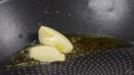 Place the crushed garlic into a pan. And pour in the extra virgin olive oil. Heat the pan on medium heat. When it begins to sizzle, reduce the heat to low and saute the garlic until aromatic.