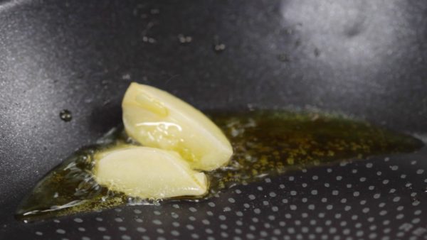 Gebt den angedrückten Knoblauch mit dem Olivenöl in die Pfanne. Bratet den Knoblauch kurz in der Pfanne an bis er aromatisch ist.