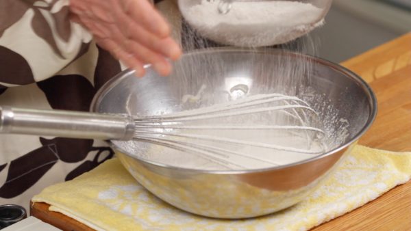 Combine the cake flour and baking powder and sieve it one time beforehand. Sieve the flour once more into the bowl of the egg mixture.