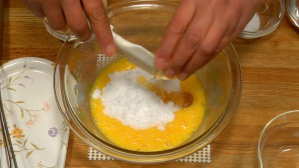 Let's make batter for Dorayaki. Crack the room temperature eggs into a bowl and lightly beat with a whisk. Add sieved Johakuto white sugar and honey to the beaten egg. Pre-warm the honey if it is too thick to mix in. 