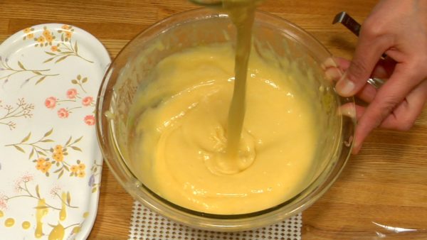 Let's adjust the thickness of the batter. Using the whisk, let the batter flow into the bowl to check its thickness. Add 1 teaspoon water (not tablespoon), mix, and see if the batter is in ideal thickness. Repeat this process until the batter flows like shown in the video.
