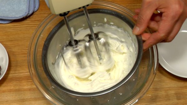Mari kita membuat krim kocok anko (pasta kacang merah). Masukkan semangkuk whipping cream ke dalam air es dan tambahkan gula. Kocok krim dengan mixer tangan listrik selama 2 hingga 3 menit hingga terbentuk puncak yang kaku. Angkat mangkuk dari air es.