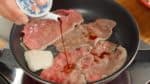 Étalez les tranches fines de bœuf. Quand le bœuf est à moitié cuit, arrosez de sauce soja. Ensuite, battez rapidement l’œuf dans un bol. 