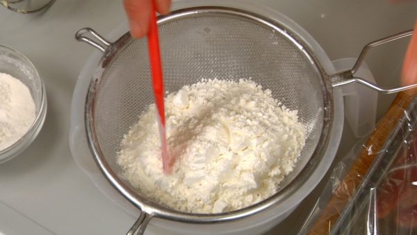 Add the baking powder to the cake flour and mix with a spatula. Sift the flour mixture into a bowl. Sift it again.

