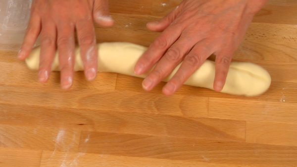 Rắc bột bánh mì trên khay bánh ngọt và đặt bột lên. Làm phẳng bột và loại bỏ khí bên trong. Cán bột thành hình trụ dài. Chia bột đã đo sẵn thành 5 phần bằng nhau. Hãy chắc chắn rằng chúng có trọng lượng bằng nhau.