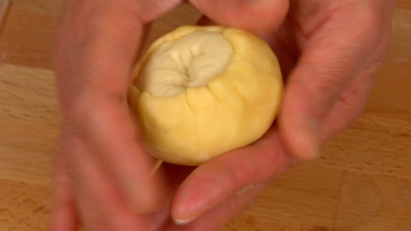 Let's shape the dough into Melonpan. Reshape each bread dough into a ball, cover with the cookie sheet and adjust the shape. Hold the dough upside down and stretch the cookie sheet up to the center.