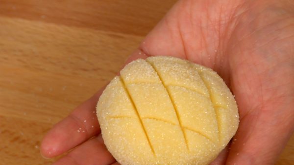 Pinch the bottom of the bread dough and dip the cookie dough in sugar. Hold the Melonpan on your palm and make a diamond pattern on top with the scraper.