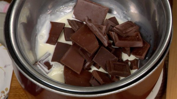 用抹刀将鲜奶油搅拌 2 到 3 次。在它开始沸腾之前，取出并放在三脚架上。将巧克力块加入奶油中。