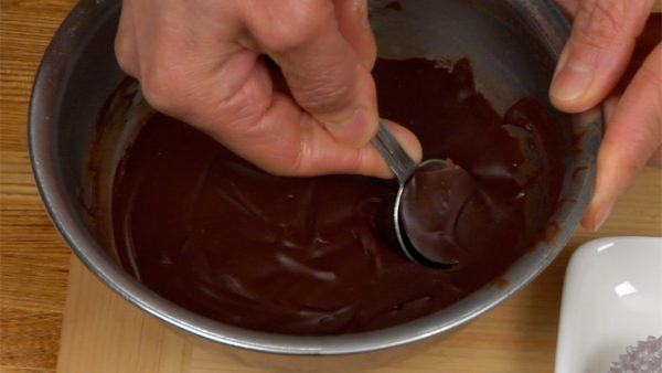 The nama chocolate is completely firm. Using a spoon, shape the chocolate into a small ball and then place it into a glassine paper candy cup.