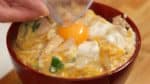 Die Ei-Fleisch-Mischung auf einer Schale frisch gedämpftem Reis verteilen. Eine Vertiefung in der Mitte machen und ein rohes Eigelb hineingeben.