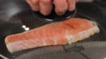 Añade aceite de nuevo a la sartén. Coloca el salmón en la sartén. Dora la parte superior primero para presentar una hermosa superficie dorada. Ocasionalmente mueve la sartén para dorar uniformemente. Tapa y dora a fuego bajo.