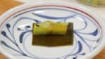 Maintenant, le yakizuke a absorbé le goût. Placez l'algue kombu et un morceau de poireau sur une assiette. Ensuite, posez le saumon dessus. 