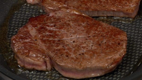 With a pair of tongs, check the under side of the steak. When it has browned thoroughly, flip the steak over.