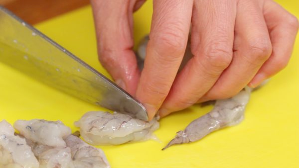 Coupez les crevettes en deux. Ces crevettes ont déjà été décortiquées et on a retiré la veine du dos. Si vous voulez savoir comment préparer les crevettes, regardez notre vidéo <a href="https://cookingwithdog.com/recipe/ebi-chili/">ebi chili</a>