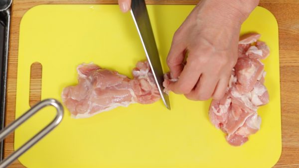 Zuerst dünsten wir das Hähnchenfleisch. Dazu die entbeinten Hähnchenkeulen in mundgerechte Stücke zerlegen. Alle Stücke sollten etwa dieselbe Dicke aufweisen. Danach das Fleisch in einen Topf mit kochendem Wasser geben.