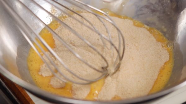 Sbattete un uovo in una ciotola e aggiungete lo zucchero grezzo. Lo zucchero grezzo si sposa benissimo con questa ricetta, ma è possibile sostituirlo anche con dello zucchero bianco classico. Continuate a mescolare.