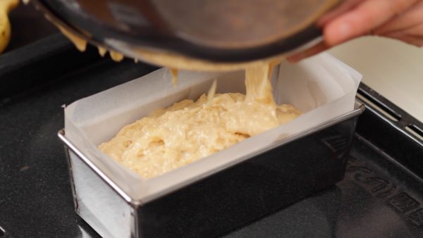 Tapissez un moule à cake avec du papier cuisson et versez la pâte dedans. Tapez le moule sur une surface plane plusieurs fois pour retirer les grosses bulles d'air. Unifiez le dessus.