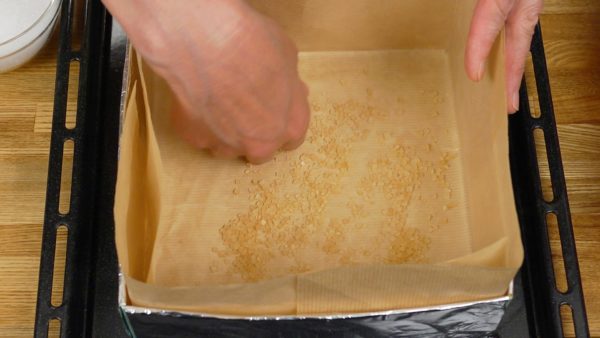 Coloque o papel Kraft ou papel manteiga na caixa de papelão embrulhada com papel alumínio e distribua os cristais de açúcar demerara grosso ou os torrões de açúcar.