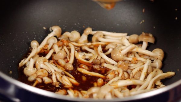 When the aroma grows stronger, add the shimeji mushrooms. Distribute the oil and stir-fry until the mushrooms are slightly softened. Stir the seasoning and add it to the ingredients. Cook for 2 to 3 minutes.