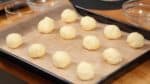 Recommencez et placez les 12 boules sur une plaque de cuisson couverte de papier cuisson. Si la pâte est trop molle pour être formée, vous pouvez aussi les déposer directement sur la plaque depuis la cuillère. 