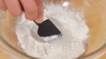 Primeiro, faça um espaço no centro da farinha de arroz moti e adicione o açúcar no local. Acrescente cerca de metade da água e dissolva o açúcar.